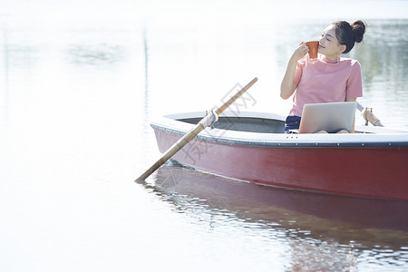 湖泊船上的女孩用笔记本电脑背景