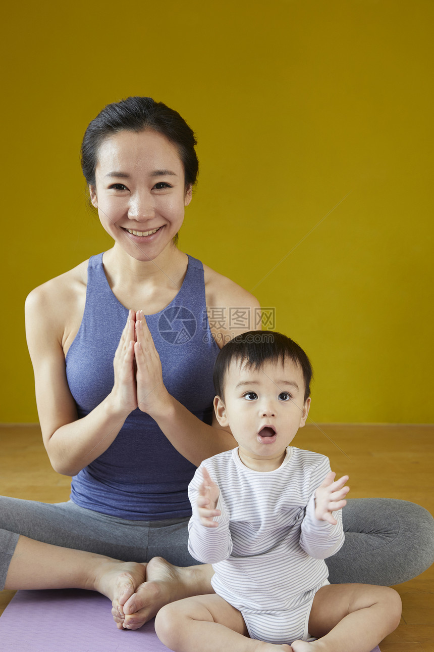 母亲做瑜伽看护着可爱的婴儿图片
