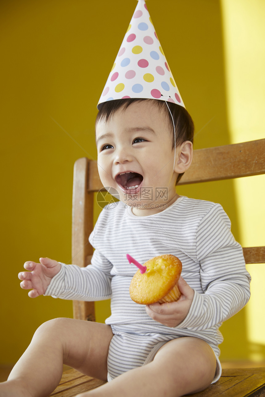 可爱的婴儿在椅子上拿着蛋糕图片