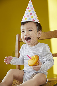 可爱的婴儿在椅子上拿着蛋糕图片
