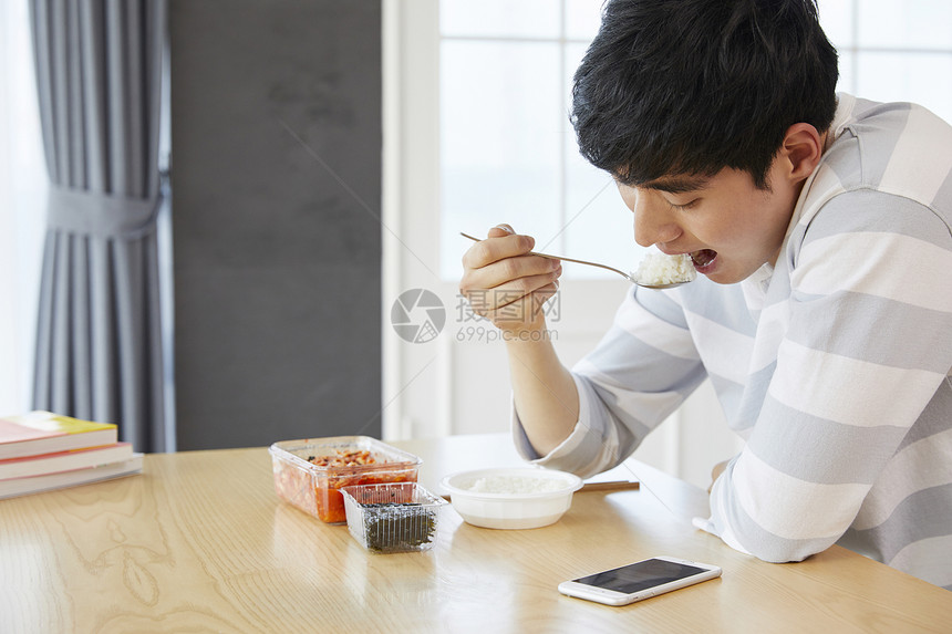 餐桌上看着手机吃饭的成年男子图片