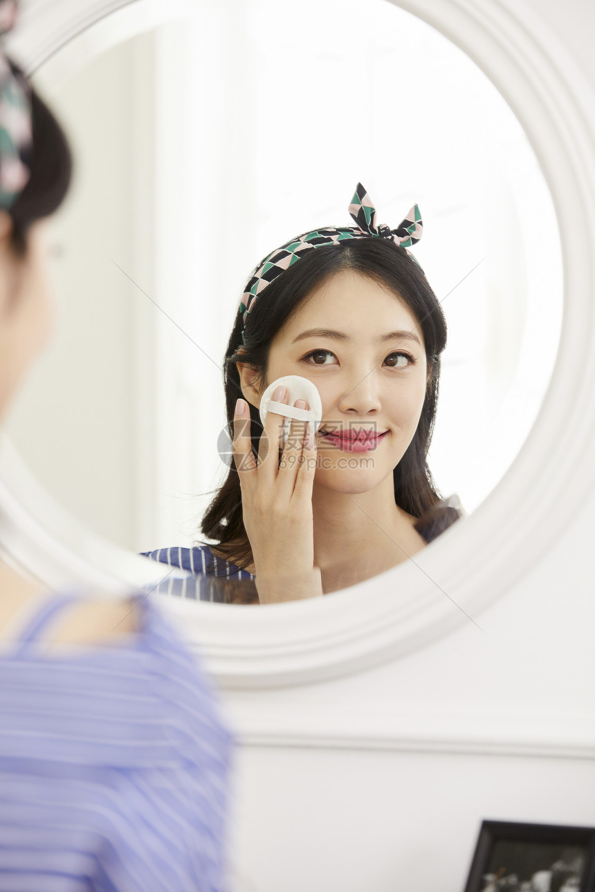 镜子前化妆的年轻女子图片