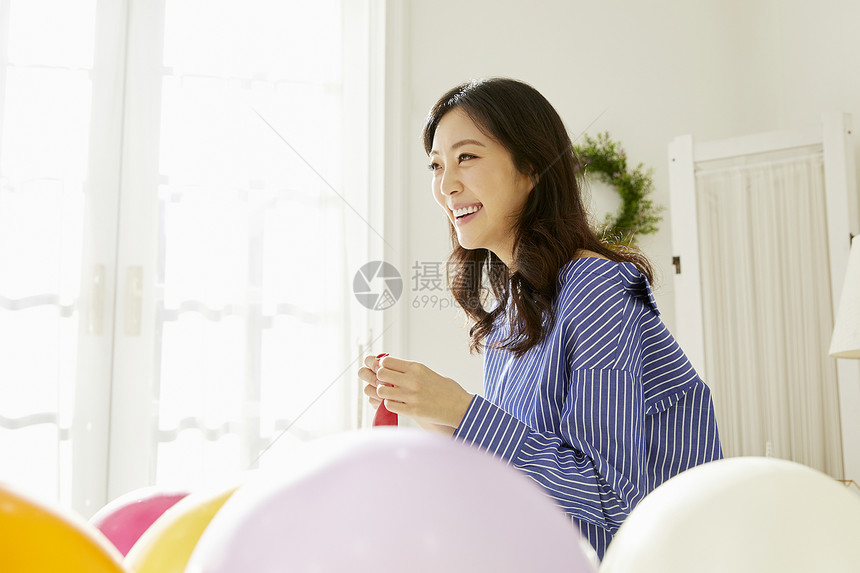 快乐年轻女子居家吹气球图片