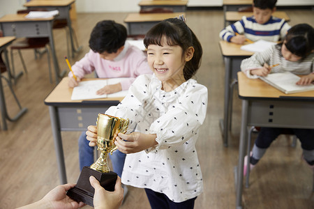 老师给小学生递奖杯图片