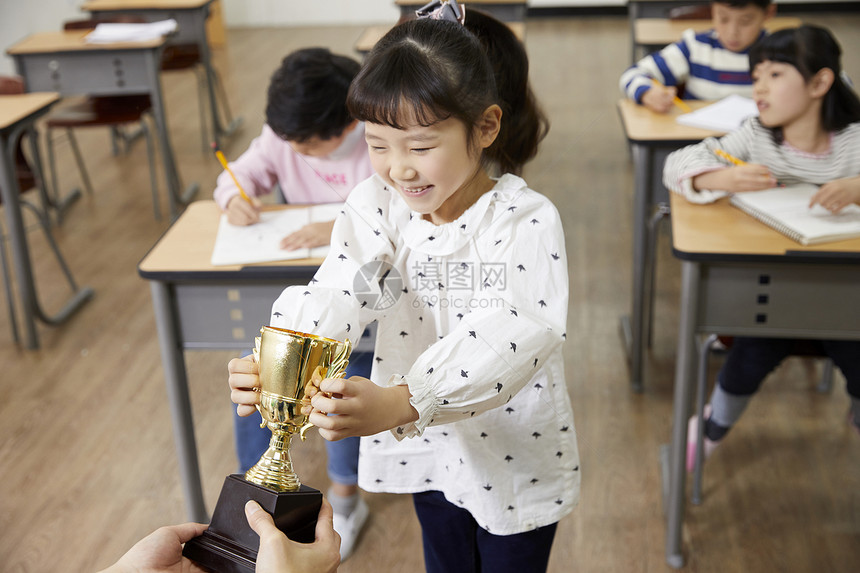 老师给小学生递奖杯图片