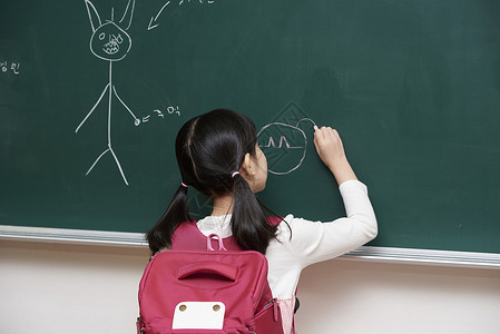 背书包的小女孩在黑板上画画背景图片