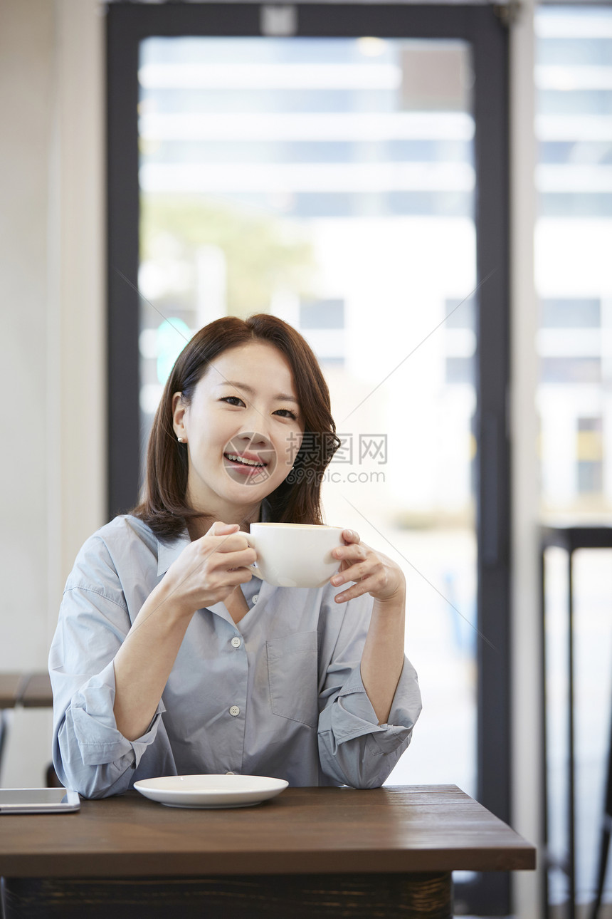 咖啡馆里喝咖啡微笑的成年女子图片