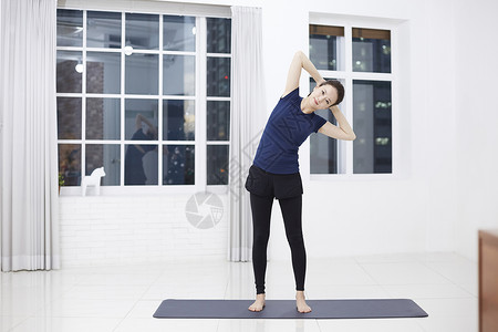 站在瑜伽垫上拉伸运动的女性图片