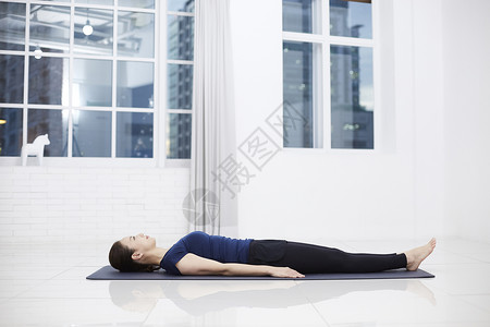 躺平在瑜伽垫上的成年女子图片