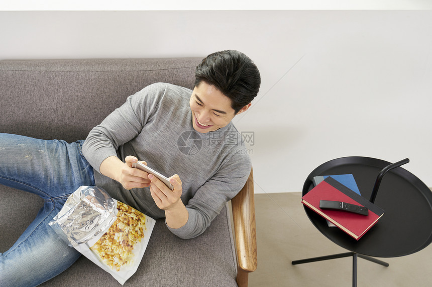 躺在沙发上看手机开心的成年男子图片