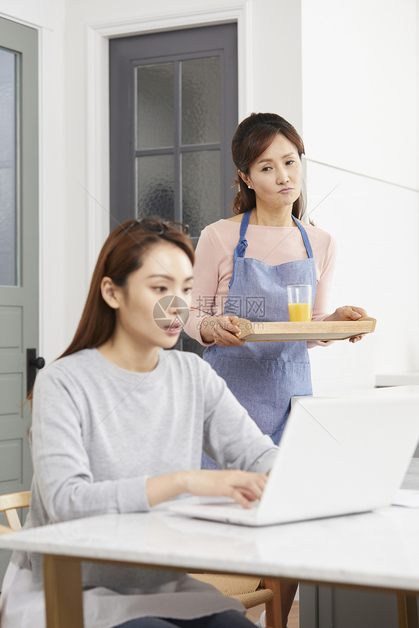 妈妈端着饮料看着女儿在家办公图片