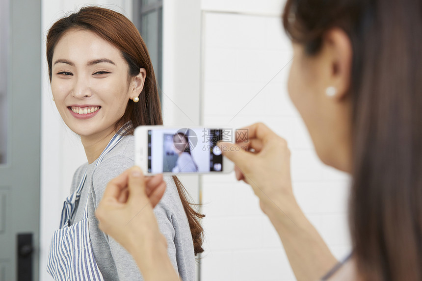 妈妈看着女儿做家务用手机拍照图片