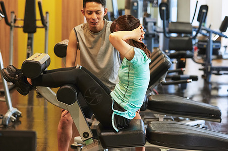 高兴人物锻炼肌肉行使在健身房的妇女和教练员图片