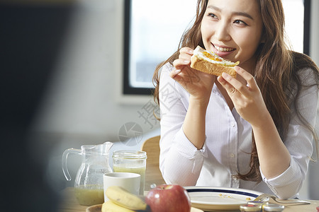 年轻女子微笑的吃着早餐吐司图片