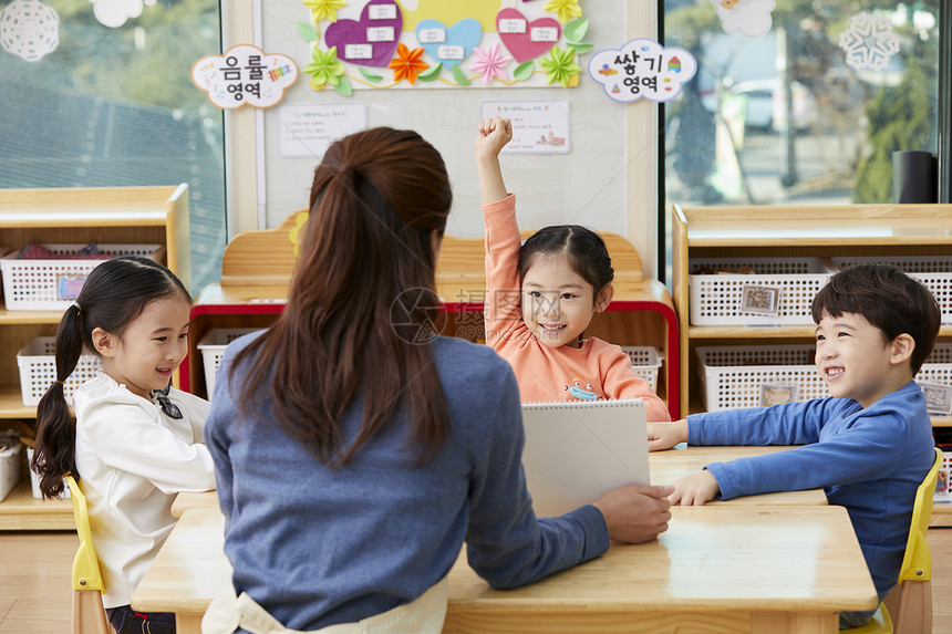 幼儿园的老师在带着学生们画画图片