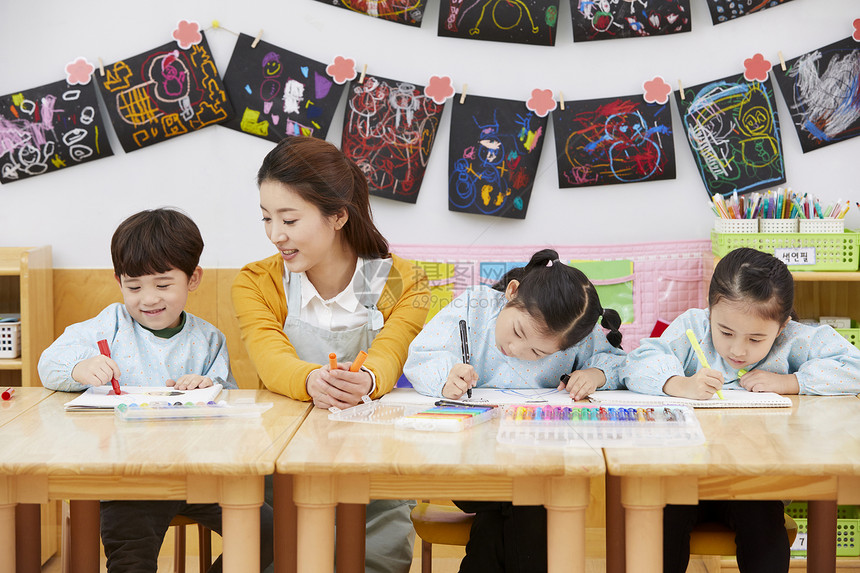 幼儿园的老师在带着学生们画画图片