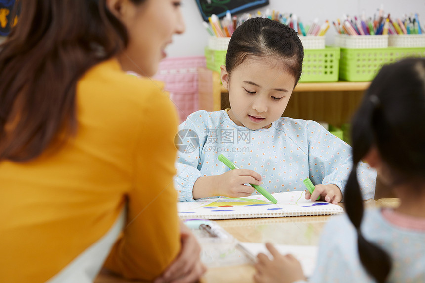 幼儿园的老师在带着学生们画画图片