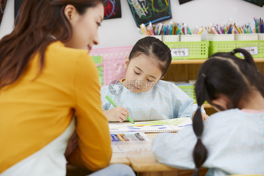 幼儿园的老师在带着学生们画画图片