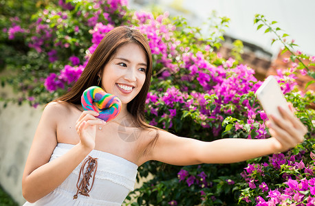 户外拿着彩色面包微笑自拍的少女图片