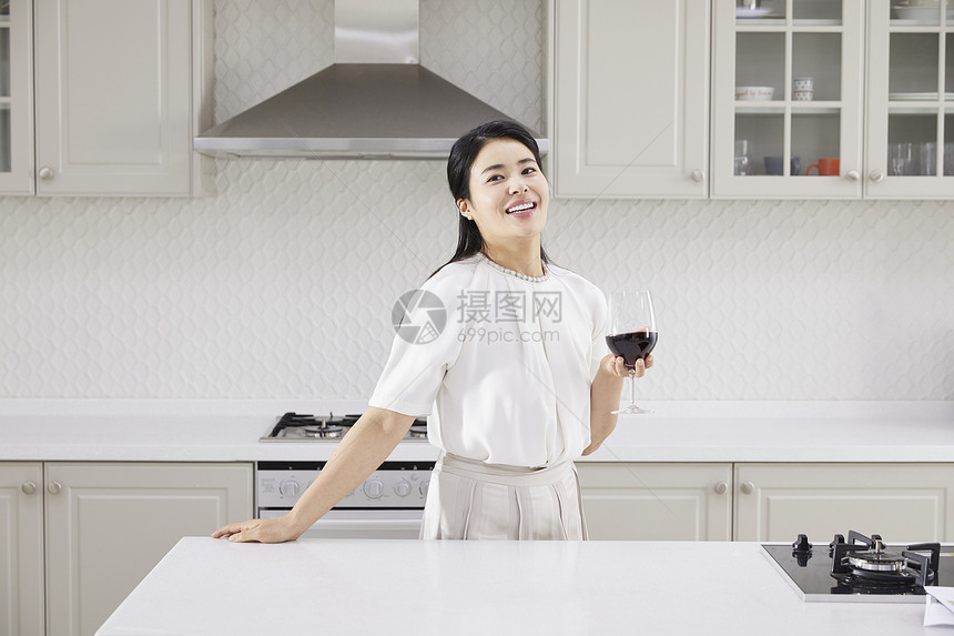 厨房里拿着红酒微笑的女青年图片