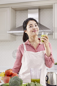 厨房里拿着果汁微笑的女青年图片
