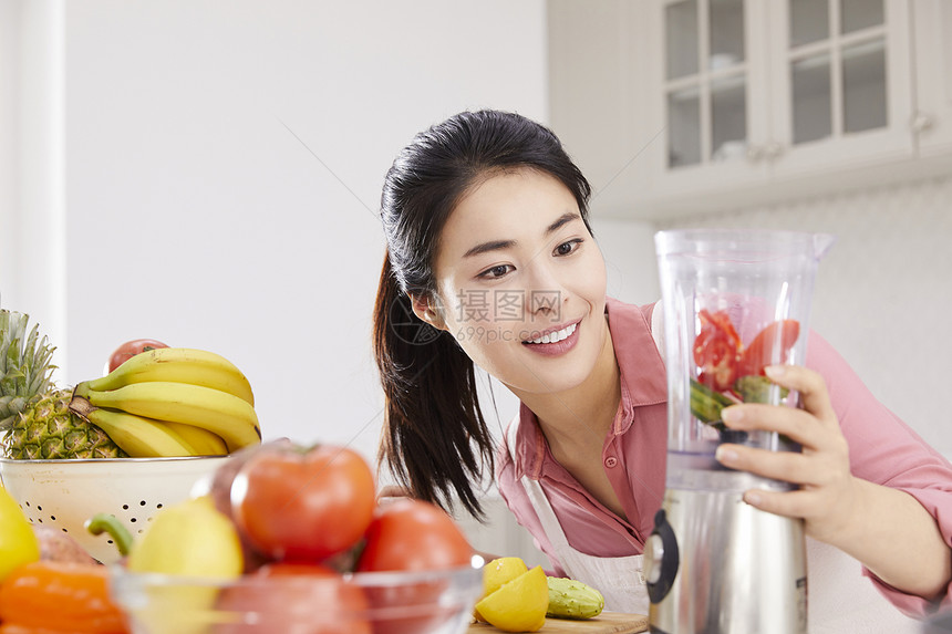 厨房里使用榨汁机的年轻女子图片