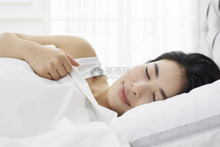床上闭眼休息的女青年图片