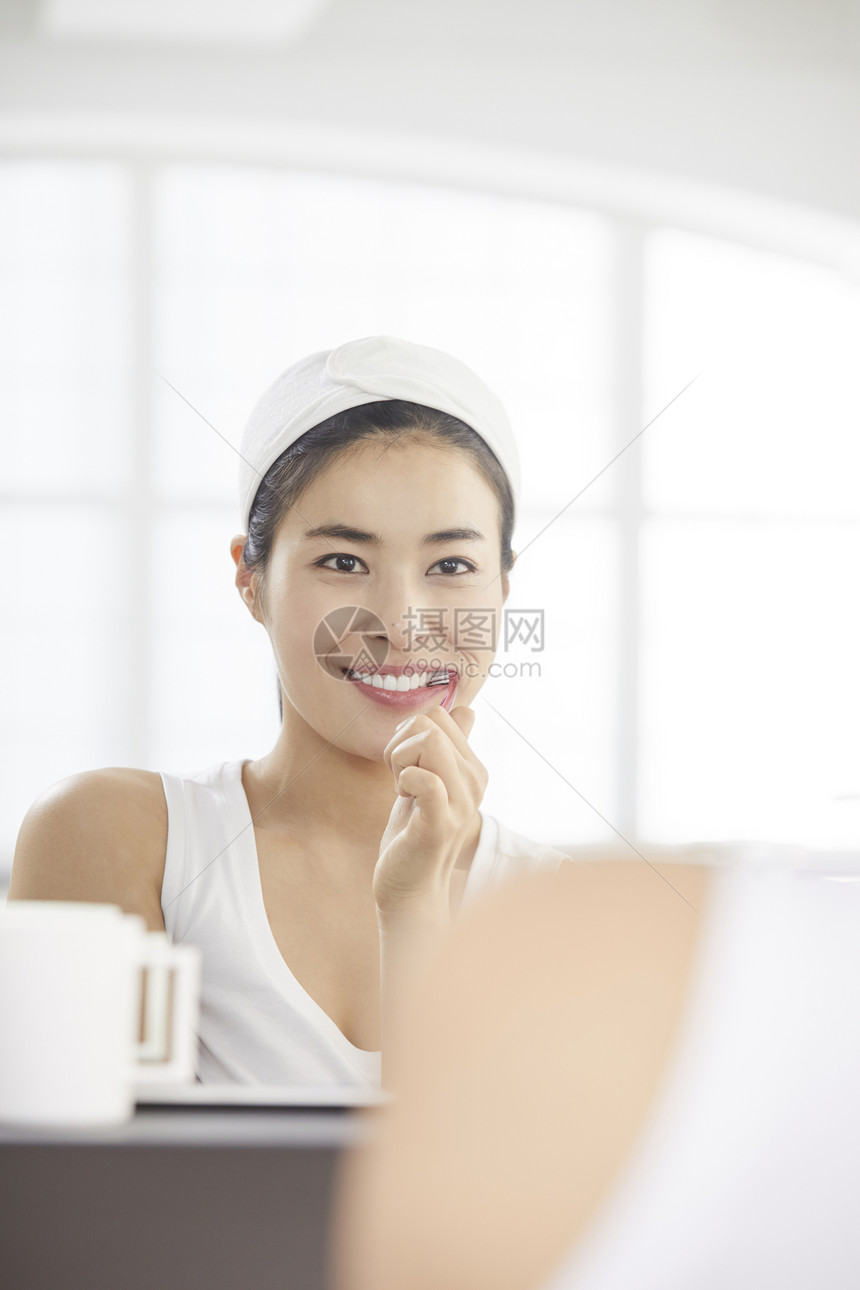 镜子前刷牙的女青年图片