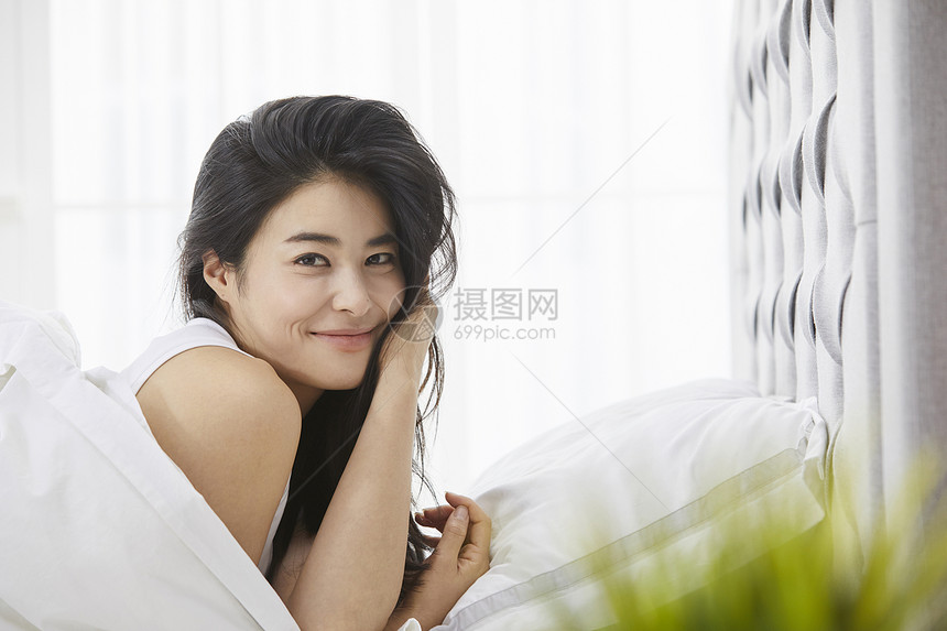 卧室里床上微笑的年轻女子图片