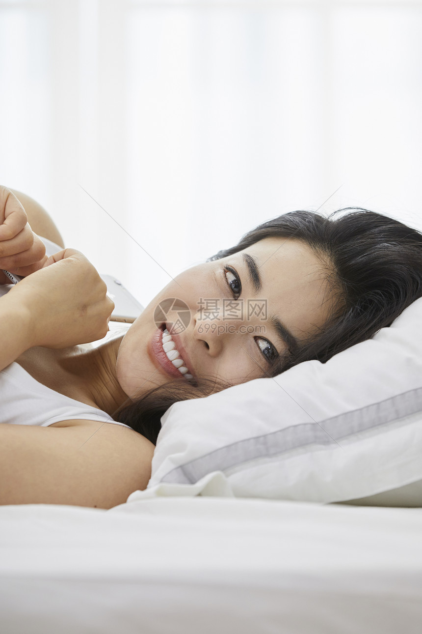 躺在枕头上微笑的女青年图片
