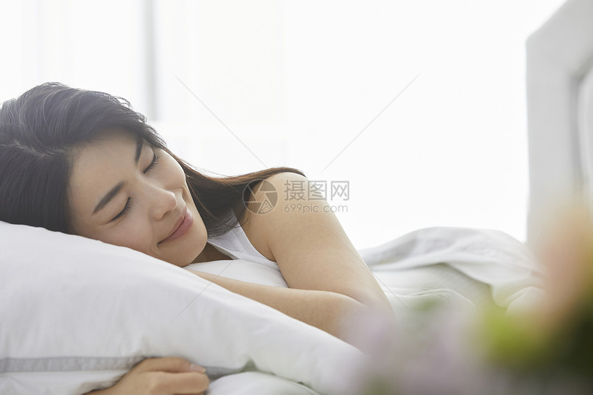 闭眼趴在床上休息的年轻女子图片