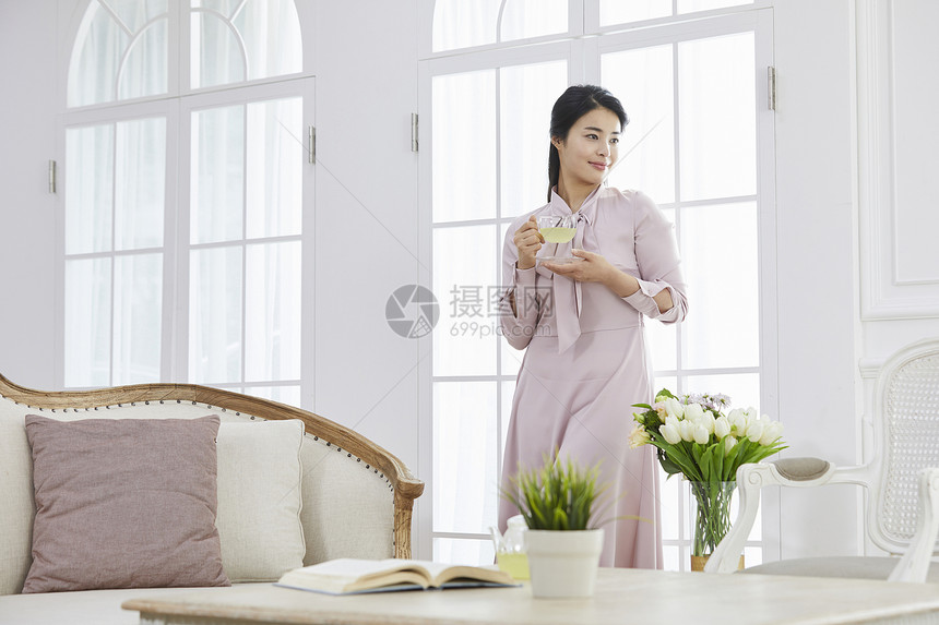 客厅里拿着茶杯的青年女性图片