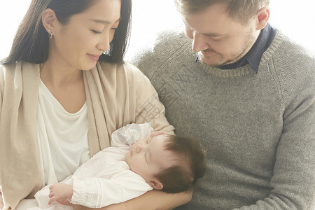 年轻夫妇看着怀里的婴儿微笑图片