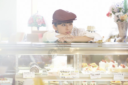 令人厌烦插座饮食做兼职工作的妇女在蛋糕商店图片