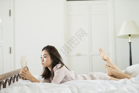 床上放松照镜子的女人图片