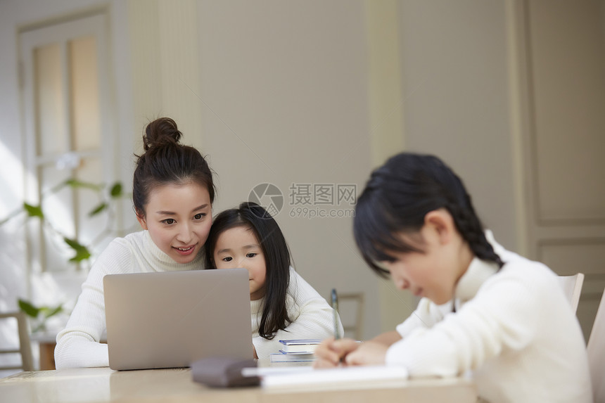小孩做作业与母亲的孩子工作在客厅图片