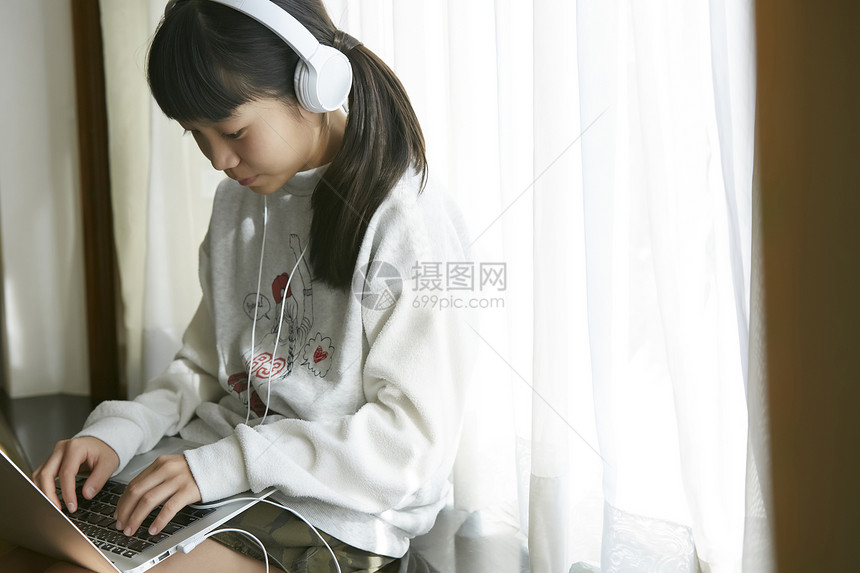戴着耳机线上学习的小女孩图片