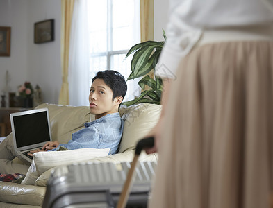 男子在沙发上用电脑回头看到妻子背景图片