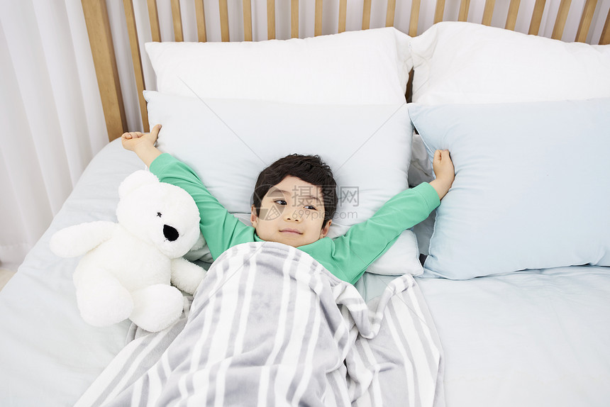 床上抱着小熊的男孩图片