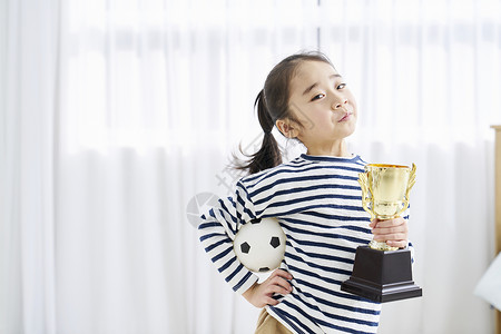小女孩开心抱着奖杯背景图片