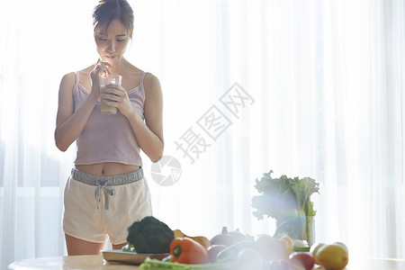 居家低头喝果汁的青年女子图片