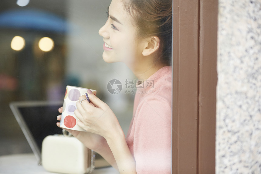 窗边拿着水杯微笑的年轻女子图片