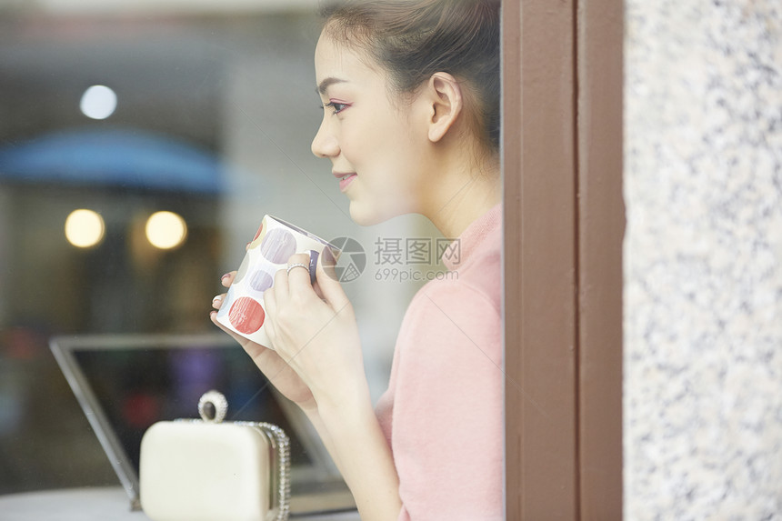 坐在窗口喝咖啡微笑的少女图片