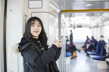 年轻美女大学生坐地铁玩手机图片