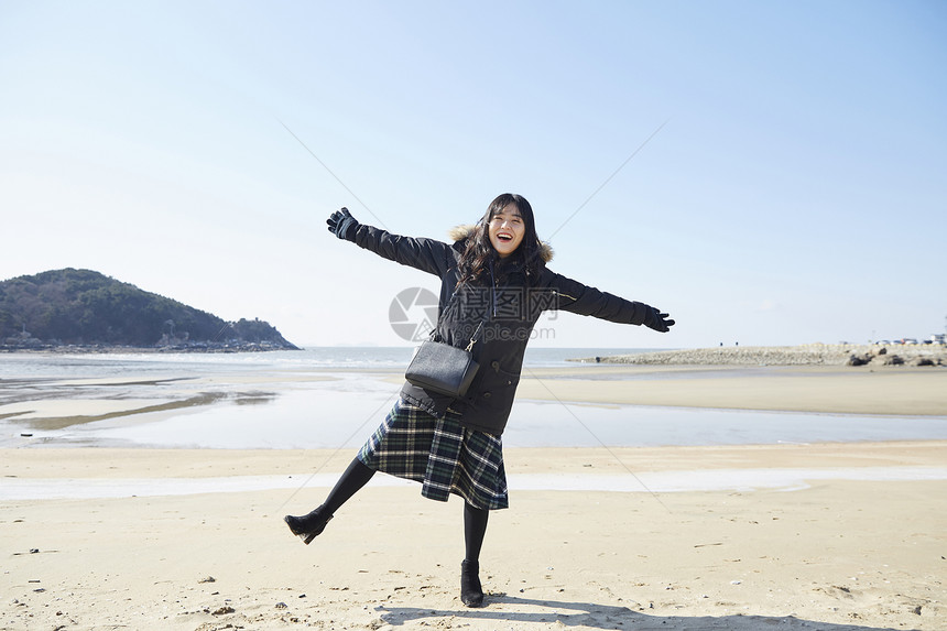 冬季海滩旅游开心的年轻女子图片