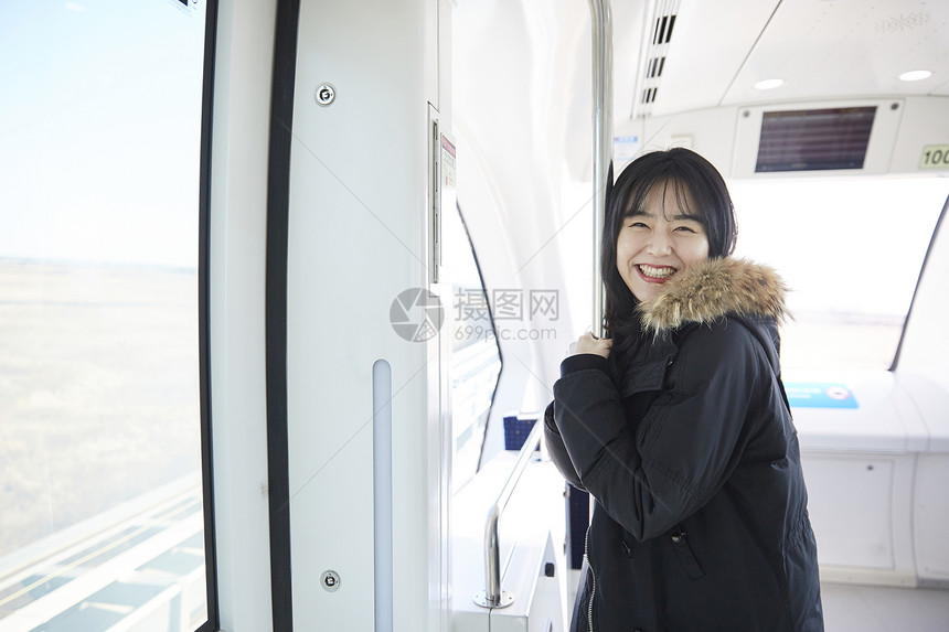 列车上抱着杆子微笑的少女图片