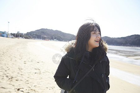 冬季穿着羽绒服海边散步的女青年图片