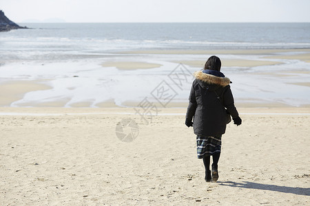 海滩上散步的年轻女子背影图片