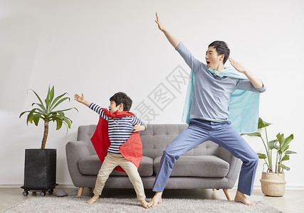 客厅里披着斗篷玩耍的两父子图片