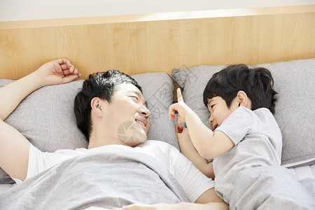 躺在床上休息的爸爸和儿子图片